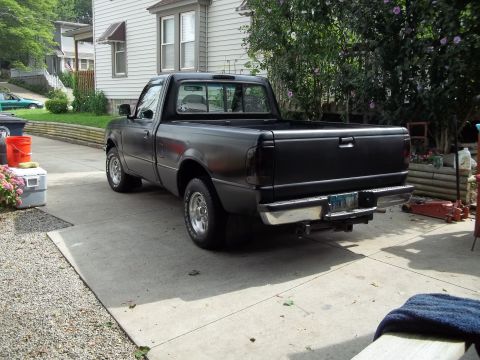 1970 Ford Ranchero - A black pickup truck is parked in a driveway, showing its rear end and side profile.