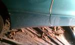 1994 Ford Probe - Side view of a teal car's lower body panel and wheel well, showing accumulated debris.