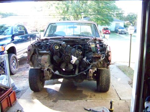 1985 Ford Bronco - Disassembled 1980s Ford truck in a garage, with a blue Dodge pickup visible to the side.
