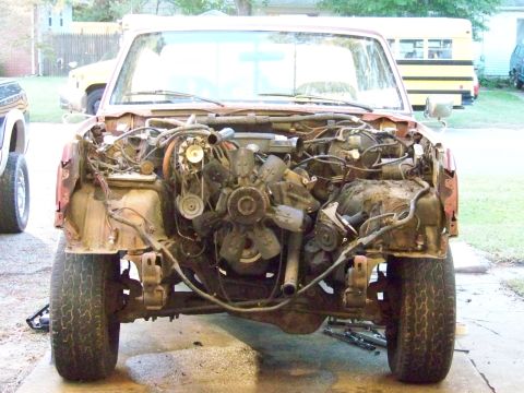 1985 Ford Bronco - This red pickup truck has had its front end disassembled, revealing the engine and suspension system.