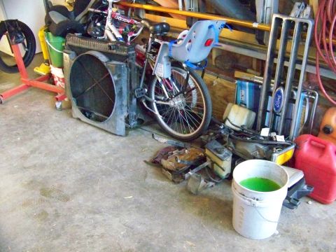 1985 Ford Bronco - A collection of automotive parts and a bicycle are stored in a garage.