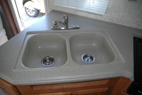 2005 Chevrolet C-6500/Kodiak - Interior view of an RV kitchenette sink area, with a glimpse of the exterior and a vehicle wheel.