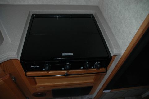 2005 Chevrolet C-6500/Kodiak - This image shows a Magic Chef stove, likely from an RV, a glass lid and four control knobs.