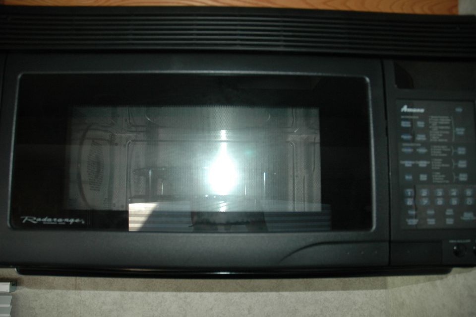 Black over-the-range microwave with a glass door and control panel. Text on door says 'Radarange'