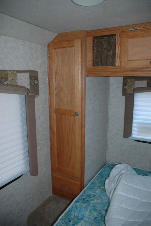 2005 Chevrolet C-6500/Kodiak - Interior view of an RV, highlighting a built-in wooden cabinet and a bed.