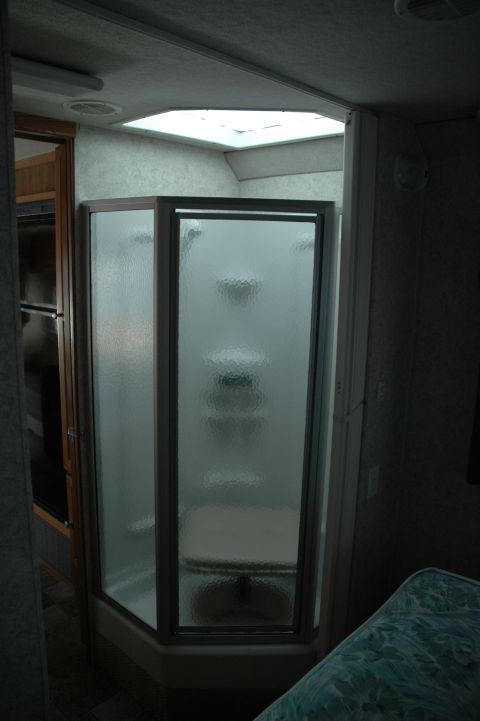 2005 Chevrolet C-6500/Kodiak - Interior view of a recreational vehicle's shower stall, frosted glass doors and a skylight.
