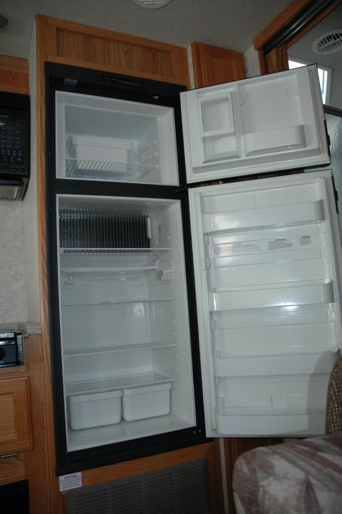 2005 Chevrolet C-6500/Kodiak - The interior of an empty RV refrigerator and freezer compartment is shown.
