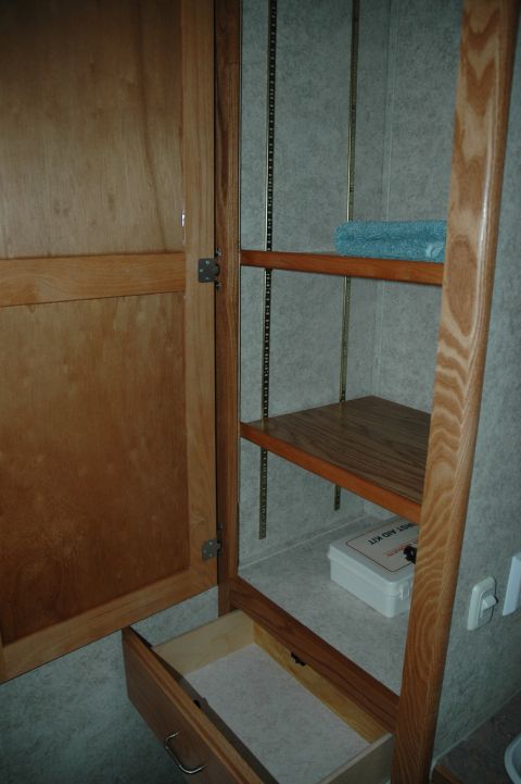 2005 Chevrolet C-6500/Kodiak - View inside a wooden cabinet with an open drawer and shelves holding a towel and a first aid kit.