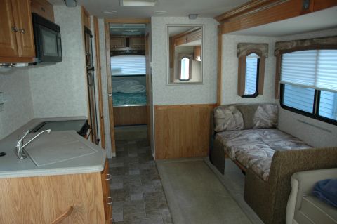 2005 Chevrolet C-6500/Kodiak - Interior view of an RV showing the kitchen area, a convertible bed, and access to the bedroom.
