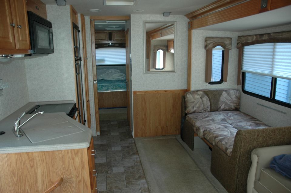 RV interior with kitchen counter, bed, and doorway to bedroom