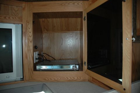 2005 Chevrolet C-6500/Kodiak - Interior view of an RV's entertainment cabinet, showing a DVD player and a TV.