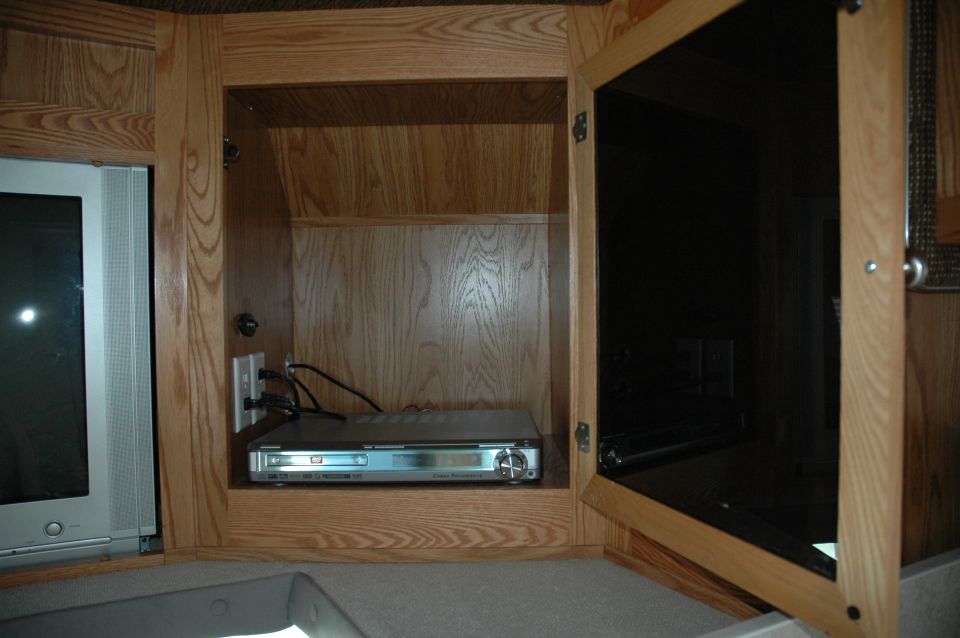 RV entertainment cabinet with wooden doors, a DVD player, and a television