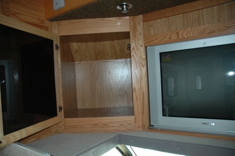 2005 Chevrolet C-6500/Kodiak - The interior of an RV features wood cabinetry and a television set.