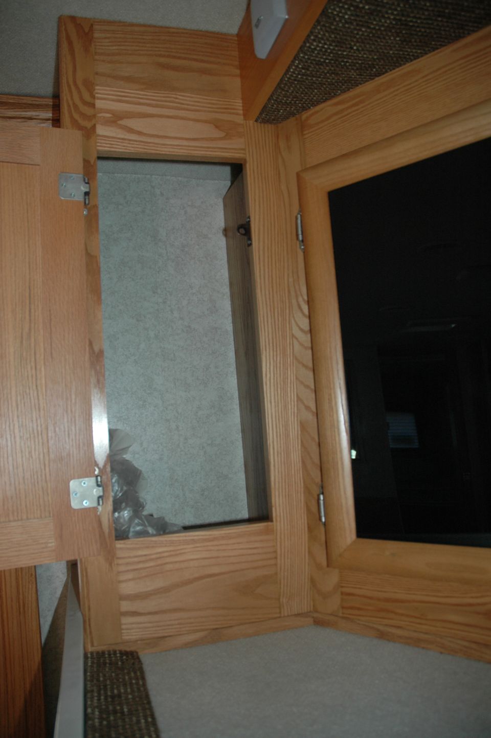 Wooden cabinets with an open compartment showing trash bags