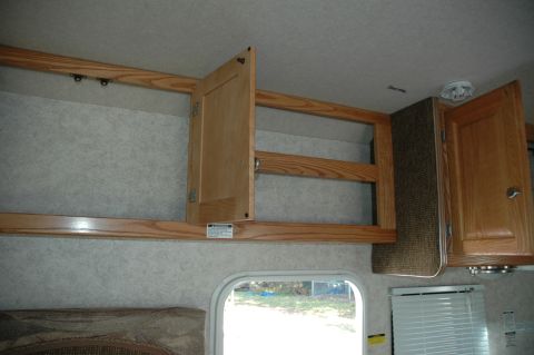 2005 Chevrolet C-6500/Kodiak - Interior view of an RV showing overhead storage cabinets and a window.
