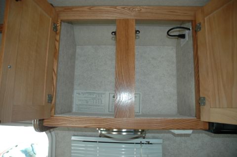 2005 Chevrolet C-6500/Kodiak - An empty cabinet interior with wood trim and a visible power outlet.