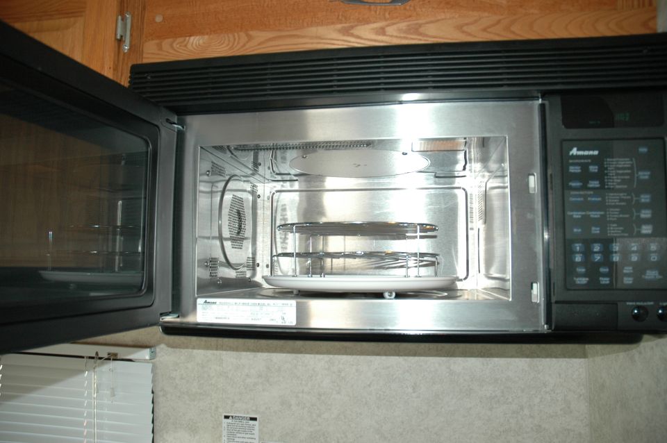 Interior of a stainless steel microwave oven with racks and a turntable