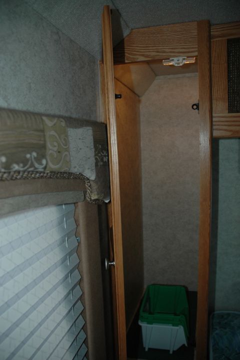 2005 Chevrolet C-6500/Kodiak - The interior of an RV shows a wooden cabinet with an open door, revealing a trash bin inside.