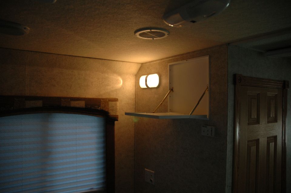 Interior RV with overhead lights, oval reading lights, and a closed wooden door
