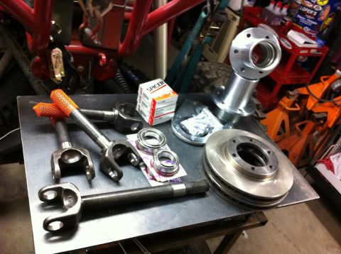 Suzuki Samurai - Various automotive axle and brake parts are laid out on a metal surface, ready for installation.