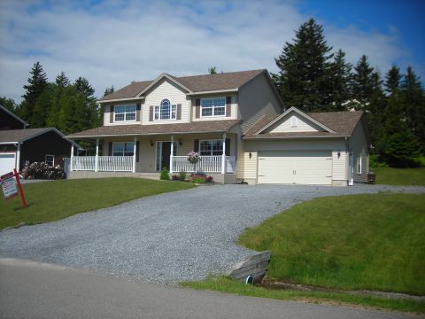 1984 Ford Bronco - A suburban house with a gravel driveway and a two-car garage is shown on a sunny day.