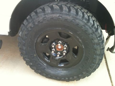 1995 Ford Bronco - A close-up view of a vehicle's tire and wheel assembly, showing aggressive tread pattern.
