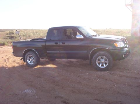 1988 Ford Bronco - Pickup truck is parked on a dirt road with a clear sky in the background.