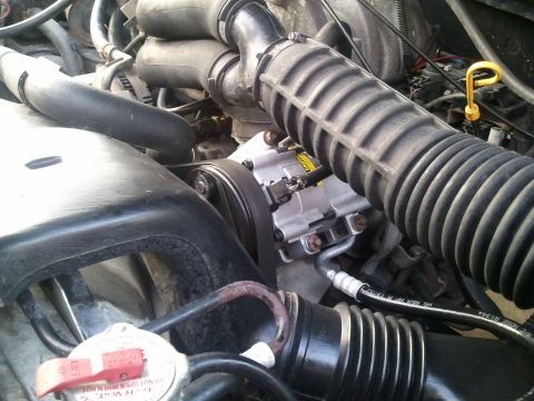 1994 Ford Bronco - Close-up view of engine components, including the AC compressor and associated plumbing.