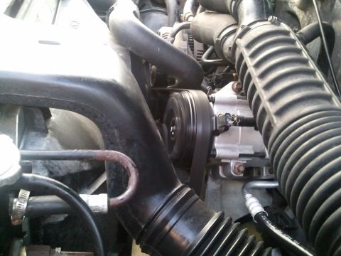 1994 Ford Bronco - Close-up of the AC compressor and belt system in an engine bay.