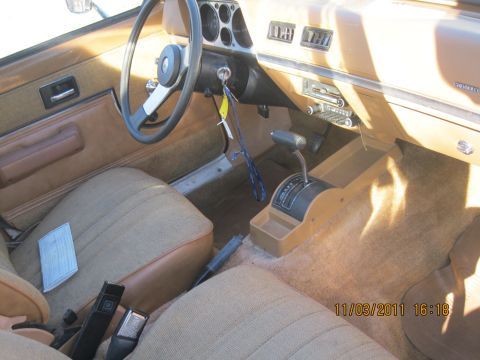 1984 Chevrolet C/K Pickup - The interior of a vehicle shows tan upholstery, a steering wheel, and an automatic transmission shifter.