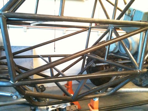 1966 Ford Bronco - A custom tube chassis buggy frame is shown with a tire and orange jack stands supporting it.