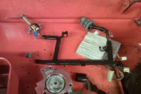 2005 GMC Yukon - A disassembled transmission wiring harness and solenoid are laid out on a red workbench.