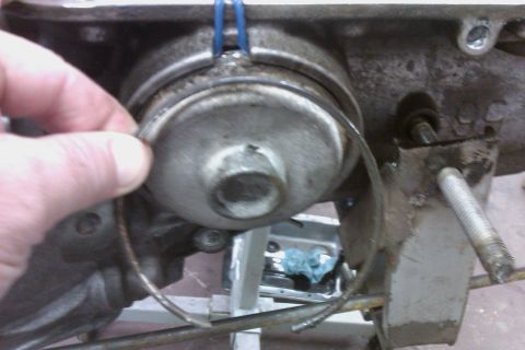 2005 GMC Yukon - A hand holds a metal ring near a component of a vehicle's transmission system.