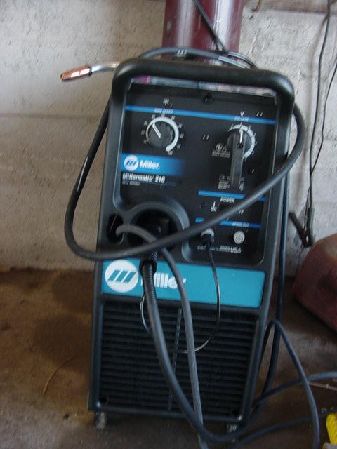 1992 Ford Bronco - A Miller Millermatic 215 welding machine is shown with its various controls and attached cables.