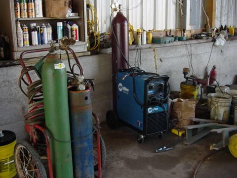 1992 Ford Bronco - A blue Miller welding machine and several gas cylinders are set up in a workshop environment.