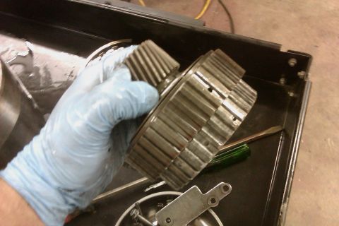 2005 GMC Yukon - A gloved hand holds a set of transmission gears over a toolbox containing other parts and tools.
