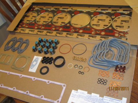 1984 Ford Bronco - A collection of engine parts, including a head gasket and various seals, are arranged on a cardboard surface.