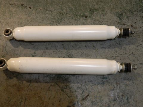 1979 Ford Bronco - Pair of white shock absorbers, likely for a vehicle, shown on a concrete surface.