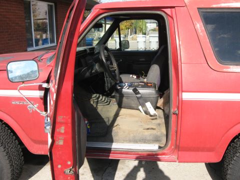 1981 Ford Bronco - Interior view of a red 1981 Ford Bronco with the driver's side door ajar.