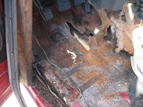 1981 Ford Bronco - The floor of a 1981 Ford Bronco shows significant rust and deterioration, particularly around the driver's side pedals.