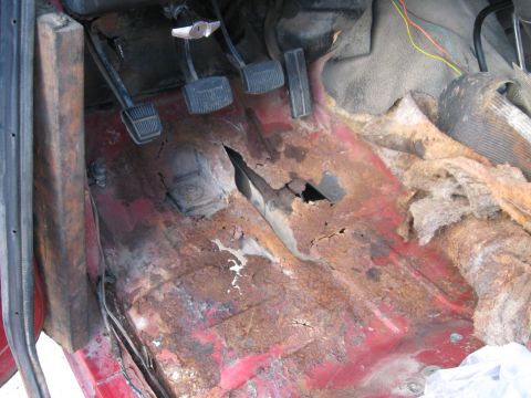 1981 Ford Bronco - The floor of this vehicle is severely rusted and has holes, indicating significant structural damage.