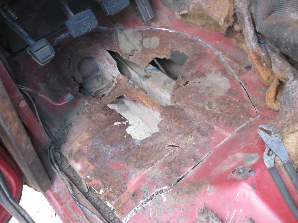 1981 Ford Bronco interior floor pan showing severe rust damage and pedals