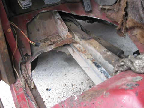 1981 Ford Bronco - Vehicle interior floor pan and frame showing significant rust damage and exposed wiring.