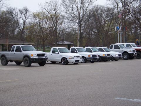 1989 Ford Bronco - A line of Ford Ranger pickup trucks are parked in an outdoor lot.