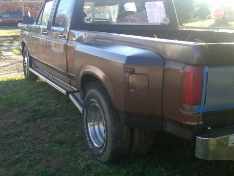1988 Ford F-350 - This dually truck shows signs of rust and wear, with a two-tone paint scheme on the rear fender.