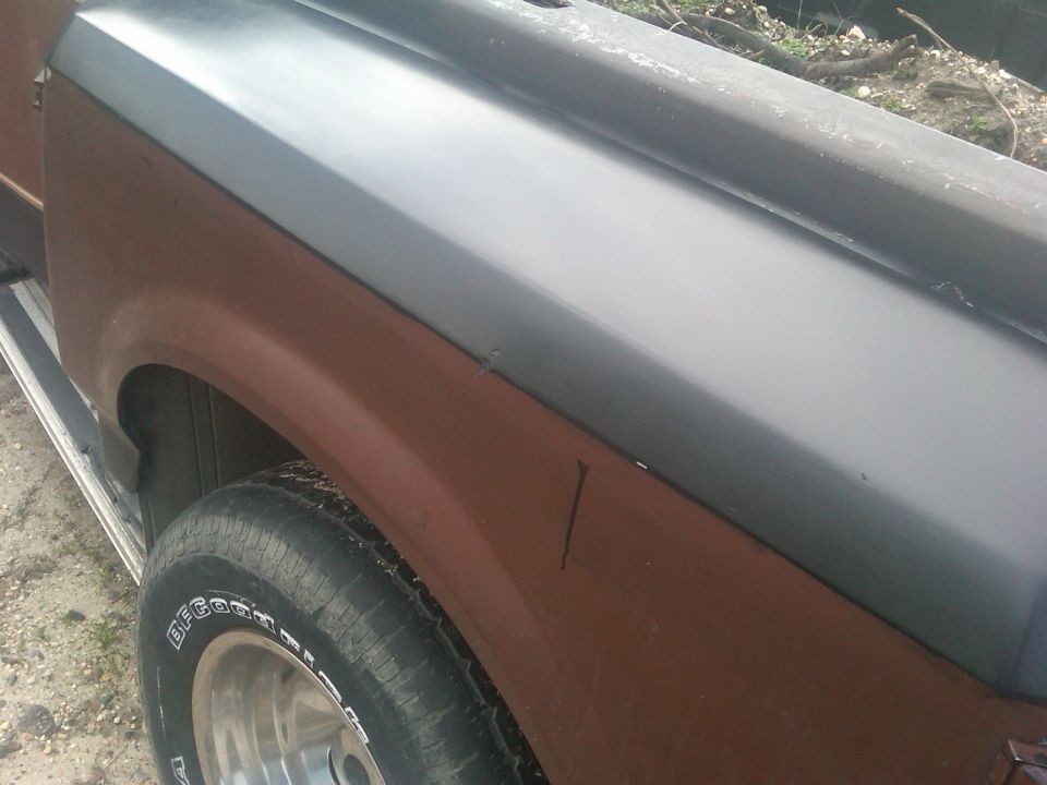 Side close-up of pickup fender with flat black upper and brown lower paint, BFGoodrich tire on alloy wheel