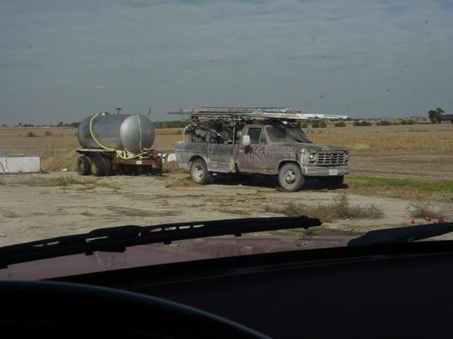 Purple pickup truck with ladder rack, towing a silver water tank trailer