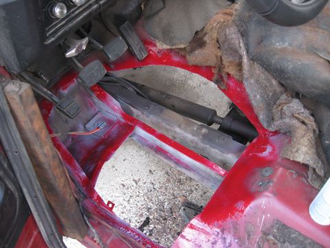 1981 Ford Bronco - The interior floor of a 1981 Ford Bronco shows exposed metal and red paint, with pedals and drive shaft visible.