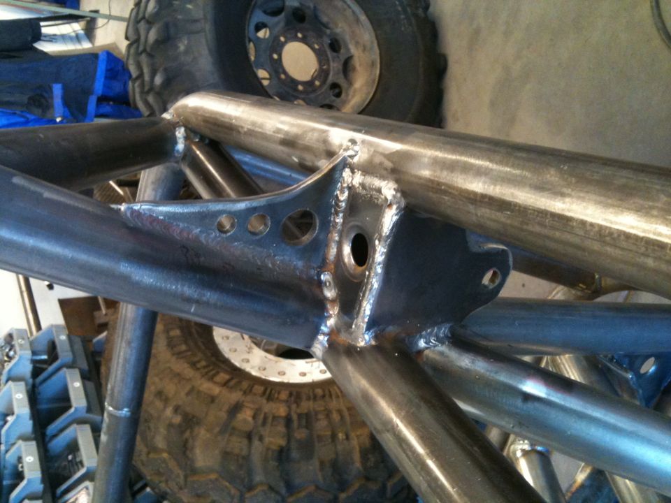Custom metal roll cage with visible welds and mounting points, large tires in background