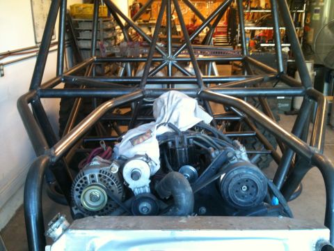 1966 Ford Bronco - The engine and roll cage of a custom-built off-road buggy are visible in this garage setting.